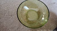 Top view of a large green glass serving bowl with textured pattern on carpet