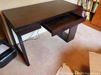 Full view of black pressed wood desk showing top surface and extended drawer pulled out