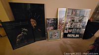 Image showing 6 poster size framed artworks arranged on the floor.