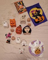 Various Halloween decorations including candle holders, pumpkin and ghost ornaments, witch head ornament, a Halloween flag, and some pumpkin carving tools.