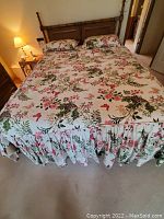 Front view of queen-sized bed covered with floral patterned bedding, wood headboard visible.