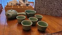 Full Korean celadon tea set displayed on wooden table with wrapping paper and box in background