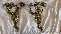 Pair of Baroque-style brass candle wall sconces with three holders each, detailed with leaves and petals