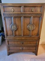 Full front view of the real wood dresser with distinctive brass hardware and carved wooden details.