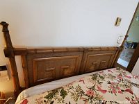 Front view of the wooden queen size headboard with floral bedspread visible at the bottom.