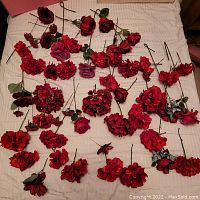 Full lot showing multiple artificial red flower stems laid out on a fabric surface.