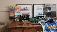 Wide shot showing collection of train memorabilia on a cabinet including framed prints, train models, books and the phone.