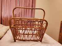 Front view of the wicker magazine holder showing basket weave design and tall handle.