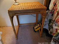 Front and sides view of the wicker side table showing bamboo-style legs and woven top edges.