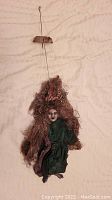 Full view of the witch marionette puppet showing entire figure including control bar, hair, and clothing.