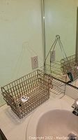 Single rectangular metal wire basket rack mounted or placed near mirror above sink