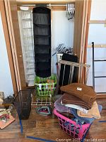 Full view of closet with hanging organizers, laundry baskets, folded towels and sweaters, drying rack and other closet accessories.