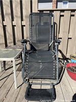 Front view of black gravity chair showing mesh fabric and metal frame with attached footrest and armrests with cup holders