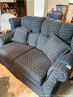 Front view of the patterned fabric love seat with two pillows showing upholstery and armrests.