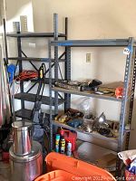 Photo showing two grey metal shelving units with various items stored, shelving shows wear.