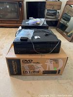 Front view of Pioneer DVL-909 and CLD-52 stacked on the DVL-909 retail box with cables on top