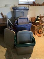 Overview of three plastic totes stacked and multiple lids leaning inside and outside the totes.