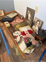 Wide view of lot items arranged on wooden surface including books, photos, coffee grinder, harmonica, handkerchiefs and yardstick