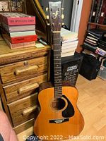 Yamaha FG-400A acoustic guitar leaning on a wooden dresser, showing overall body and neck condition.