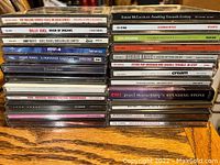 Photo of the lot showing 25 music CDs stacked in jewel cases with visible spine titles of artists including The Rolling Stones, Billy Joel, Sarah McLachlan, and others.