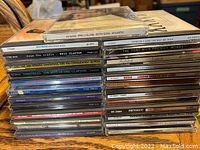 Photo of two stacks of 25 music CDs showing various artists and album titles