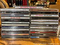 Photo showing a stack of 25 used CDs from various artists and genres.