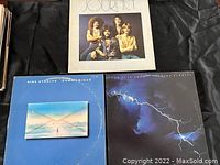 Three LP record album covers placed on a black background, showing Journey album, Dire Straits Communiqué and Brothers in Arms by Dire Straits.