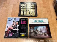 Three LP record box sets laid out flat on a surface, showing covers for Lulu, HMS Pinafore and a box with multiple yellow circular labels on a black cover.
