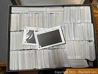 Top view of box filled with thousands of white, rectangular used stamp mounting cards.