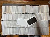Large quantity of used stamp cards arranged in rows on a table surface, showing quantity and condition.