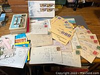 Photo showing a variety of vintage postcards and envelopes spread out on a table, some with handwritten addresses and stamps.