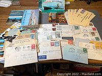 Overview of multiple vintage postcards and envelopes spread on a table, showing various stamps and postmarks.