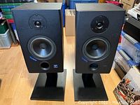 Pair of Yorkville Sound YSM1P powered speakers on black stands, front view with visible drivers and logos.