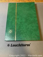 Green hardcover Leuchtturm stock book with gold stripe and emblem on the cover.