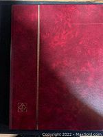Red textured stock book with gold vertical band and a corner emblem on the cover.