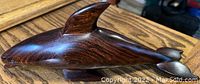 Side view showing the smooth polished finish and natural wood grain of the dolphin carving.