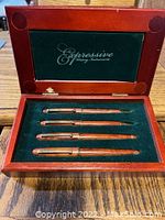 Wooden box open showing four writing instruments on velvet lining with Expressive logo