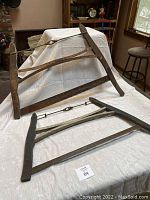 Two vintage bow saws displayed lying on a white cloth, showing their full wooden frames and steel blades.