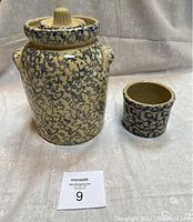 Two ceramic items: a butter churn with lid and a smaller crock, both with blue splatter on beige base