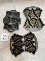 Three cast iron baking pans shown flat on table: one teddy bear shaped pan with several bear molds; two pans shaped with multiple Christmas tree molds.