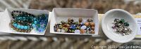 Overview of three trays holding various bead necklaces/bracelets and single earrings, showing the full lot.