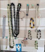 Full view of assorted costume jewelry laid out on fabric background including necklaces, bracelets, earrings, and a brooch shaped like a doll