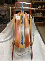 Full view of the Flexible Flyer wooden sled showing the red and natural wood slats with text and power steering mechanism