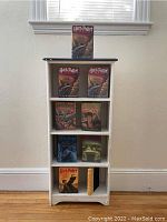 White wooden bookcase with 8 Harry Potter books and a bonus book displayed on shelves, showing front view with Harry Potter book covers visible.