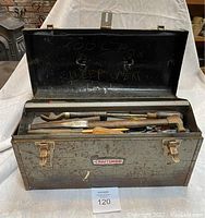 Open green Craftsman toolbox showing tools inside with marks and scratches on toolbox lid.