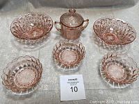 Full set of six pink Depression glass pieces arranged on a table, includes covered sugar bowl and five bowls