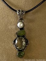 Front view of the sterling silver pendant showing faceted lemon quartz, peridot stones, and pearl on black cord.