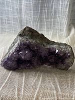 Side angle view of the amethyst crystal cluster showing its natural formation and varying purple tones.