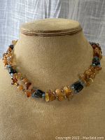 Front view of wrap-around carnelian and magnetic hematite bead necklace displayed on jewelry bust.