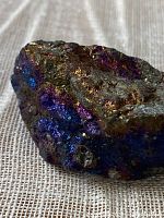 Close-up photo of the iridescent surface of the Chalcopyrite Peacock Ore mineral showing vibrant purples, blues, and gold hues.